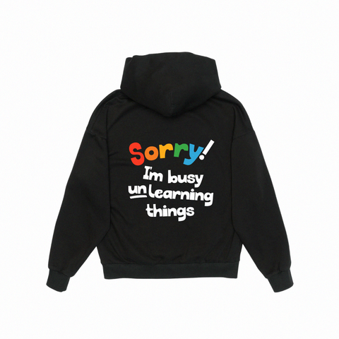 'sorry! i’m busy unlearning things' midweight black hoodie